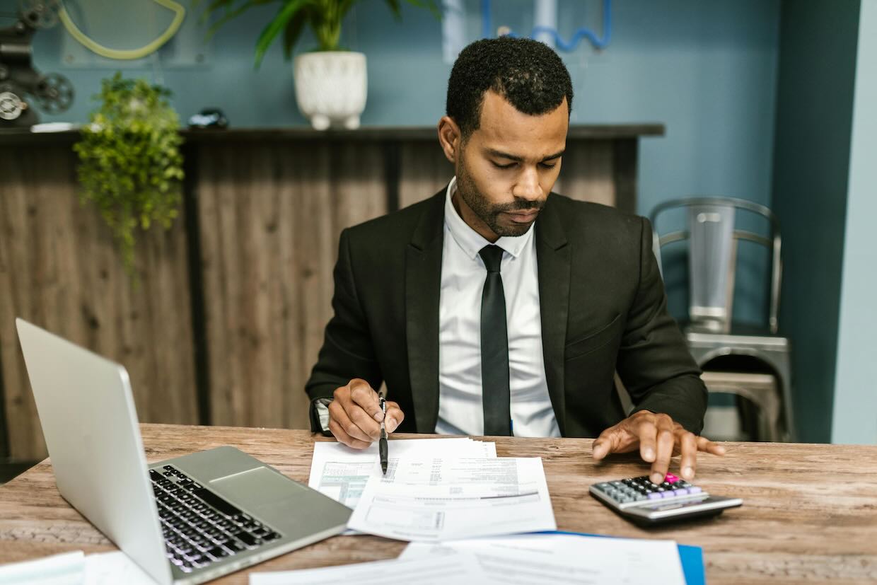 A man in a suit going over papers and using a calculator