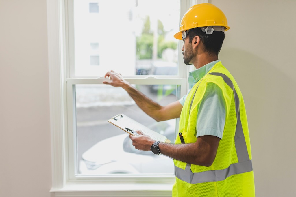 A person in a hard hat inspecting a window