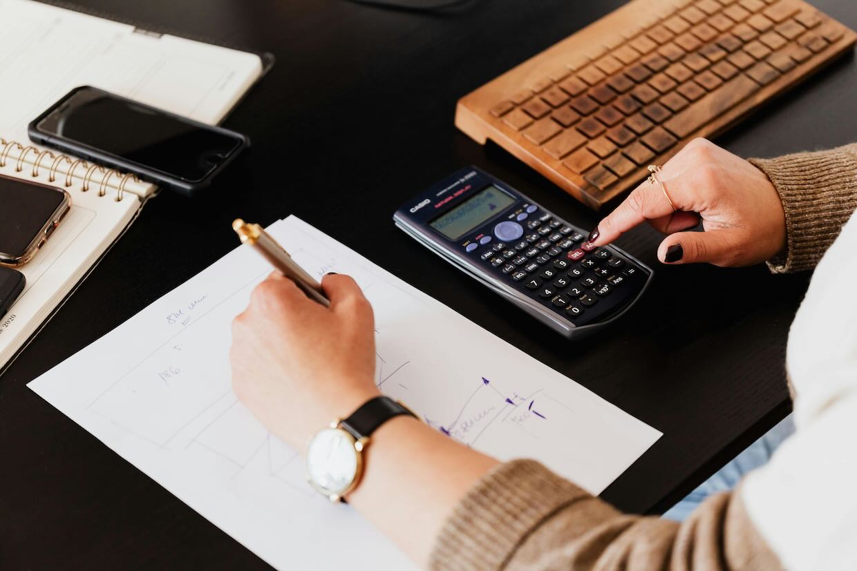 A person making notes as they use a calculator