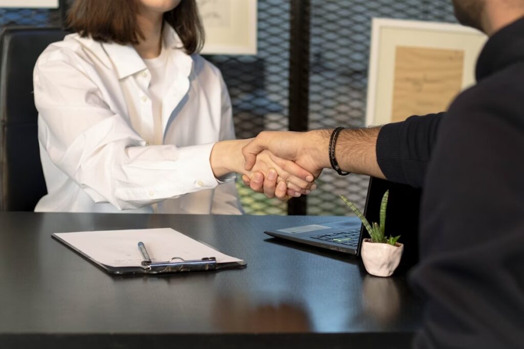 Two people shaking hands over a desk