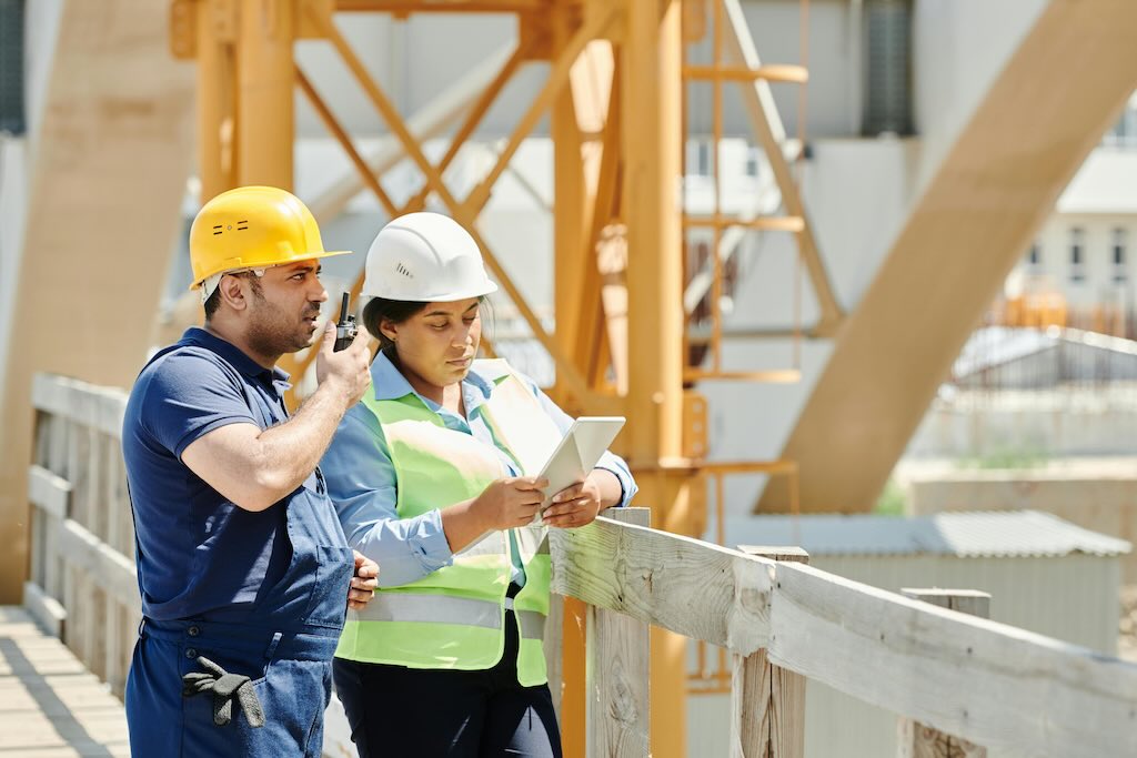 Two people standing with hard hats inspecting a construction site