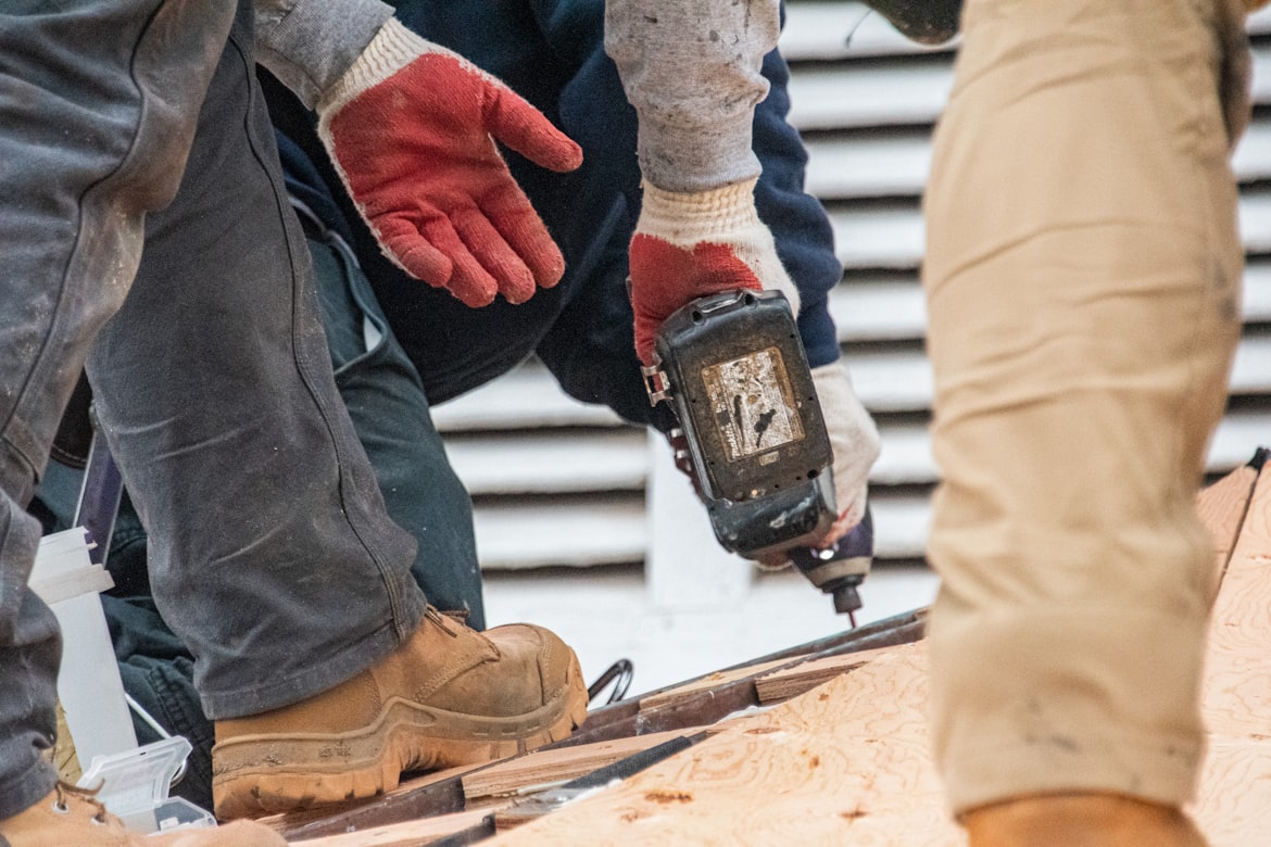 A close up of workers boots and a drill on a roof