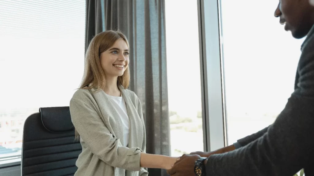 A professional looking woman shaking hands with a man in a suit